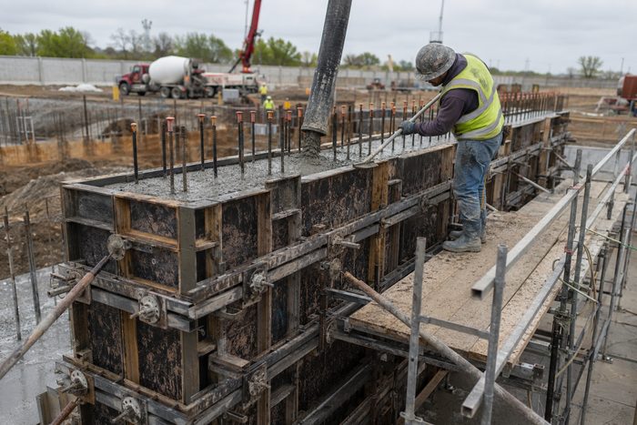 Fresh concrete being placed into braced wall formwork by pump line on a cast-in-place site