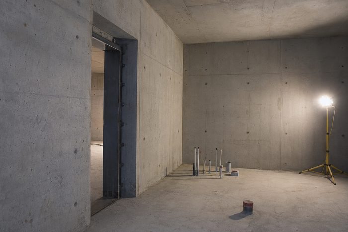 Interior of a hardened secure room under construction, with a heavy steel door set into thick cast concrete walls
