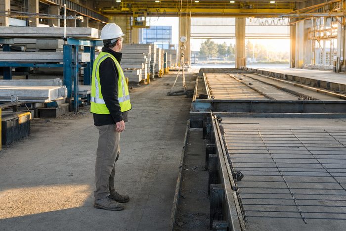 A precast concrete yard at dawn with a gantry crane loading a truck