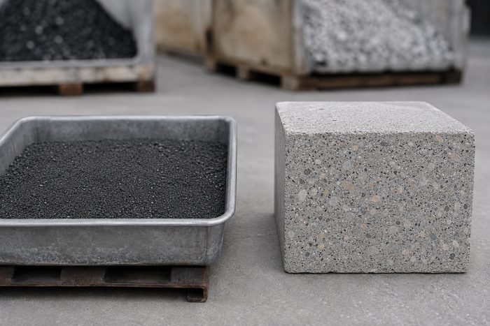 Reclaimed carbon feedstock beside a finished CarbonCrete sample block